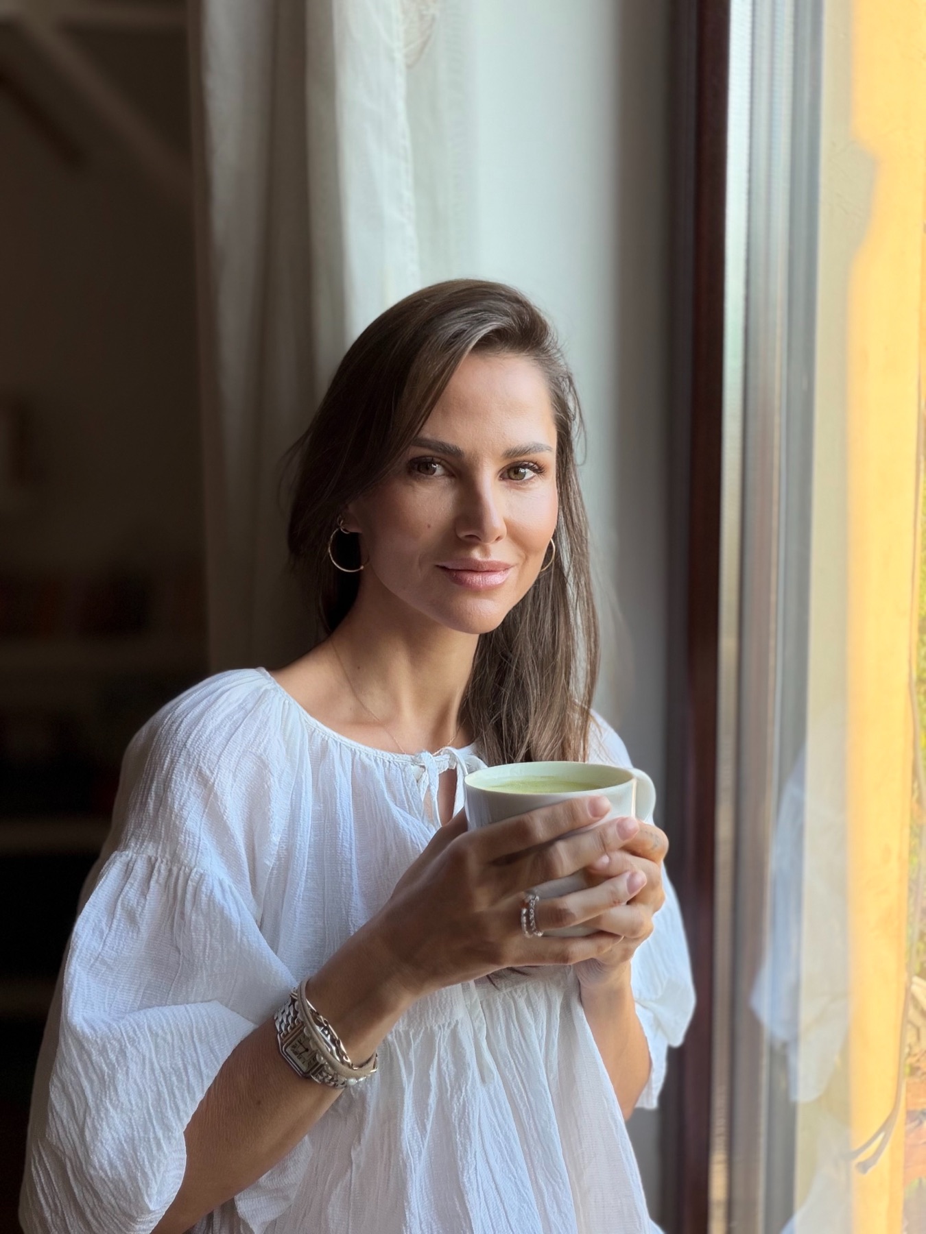 Portrait of Jani Weizman by a window, holding a cup